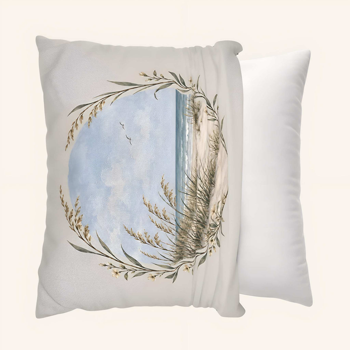 A square decorative pillow cover with a printed coastal scene showing a blue sky, ocean, sand, and sea oats in a circular wreath-like frame, showing it being slipped over a throw pillow.