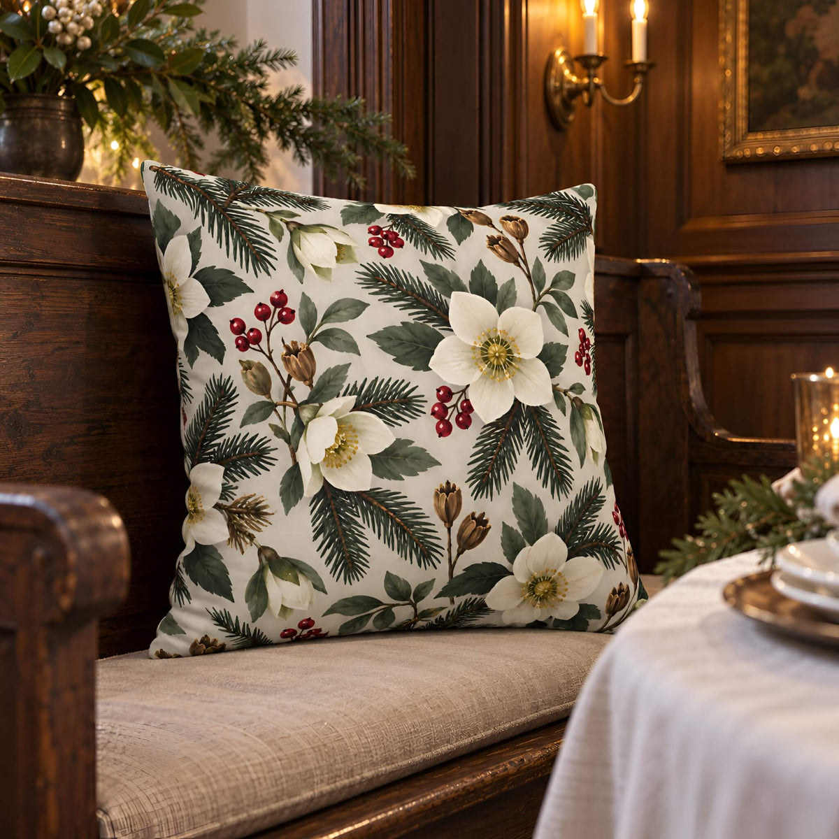 A square decorative throw pillow with a white floral and green pine pattern, styled on a wooden bench in a warm, traditional room setting.