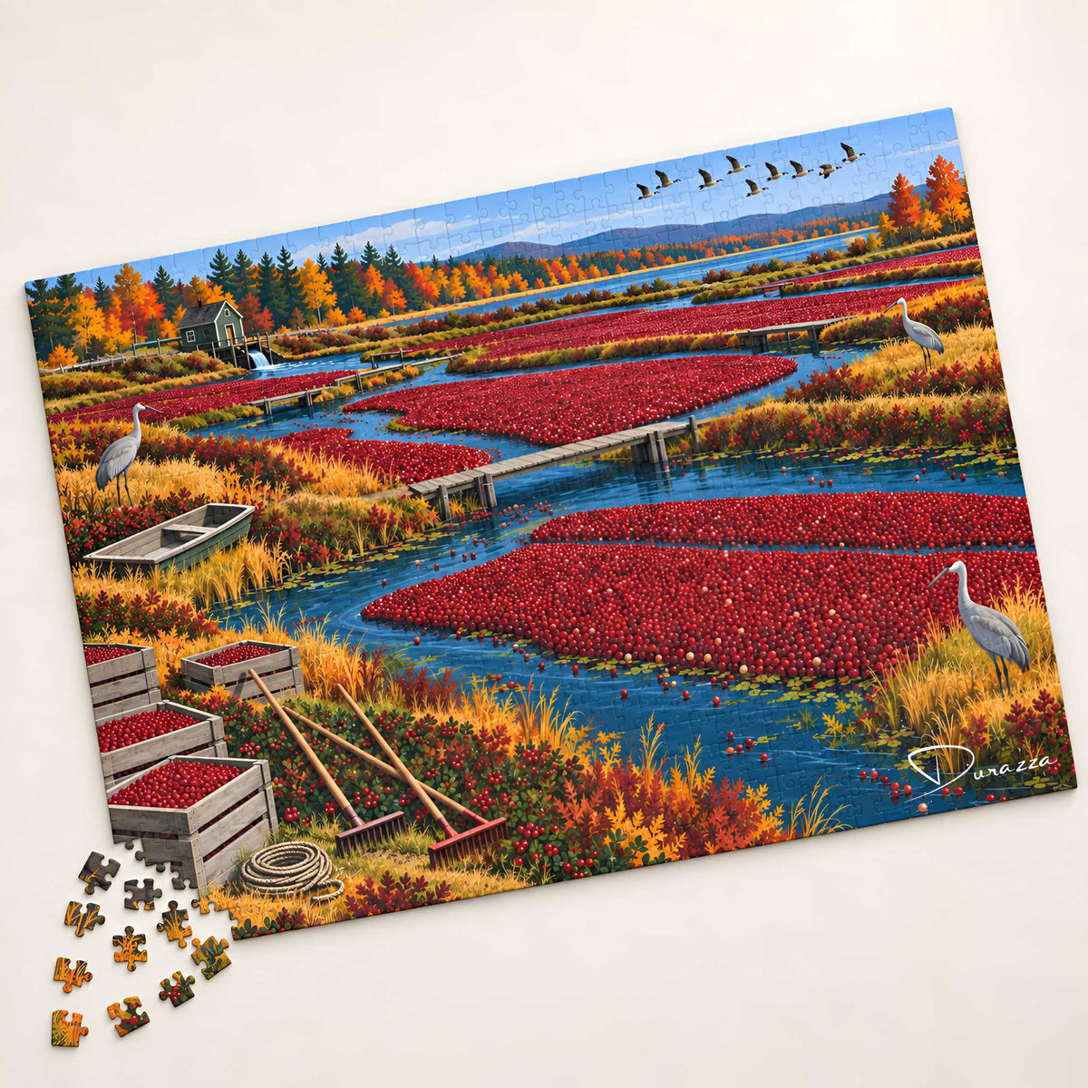 A completed jigsaw puzzle showing an autumn marsh landscape with red berry fields, blue water, trees, birds, and cranes, photographed on a light neutral background with a few loose puzzle pieces at the lower left.