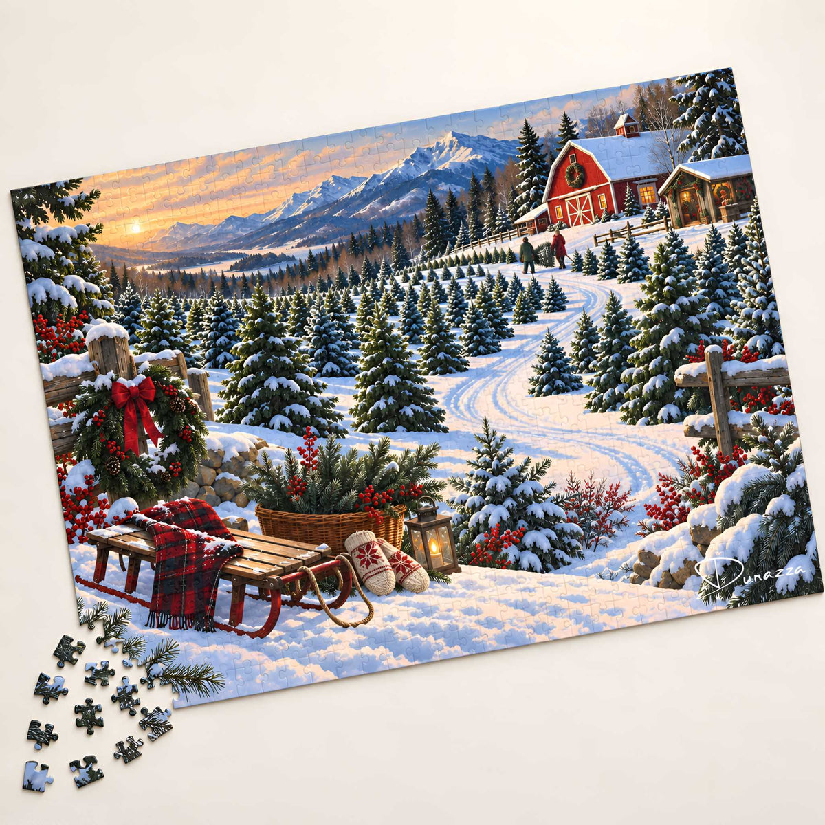 A completed winter landscape jigsaw puzzle showing a snowy mountain Christmas tree farm with a red barn, evergreen trees, mountains, and a sled in the foreground, photographed on a light neutral background with a few loose puzzle pieces at the lower left.