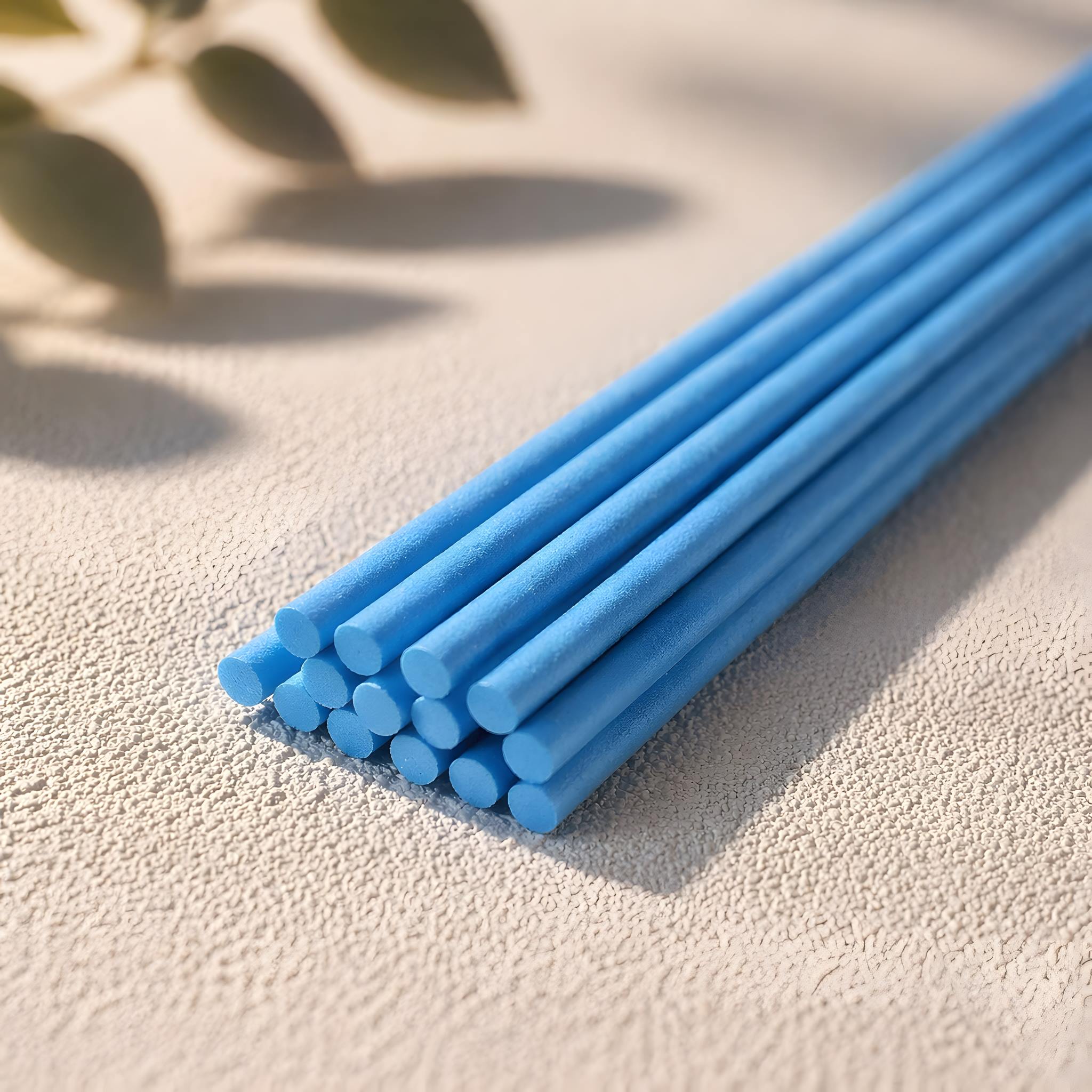 Blue diffuser reeds on a textured surface with a natural light background