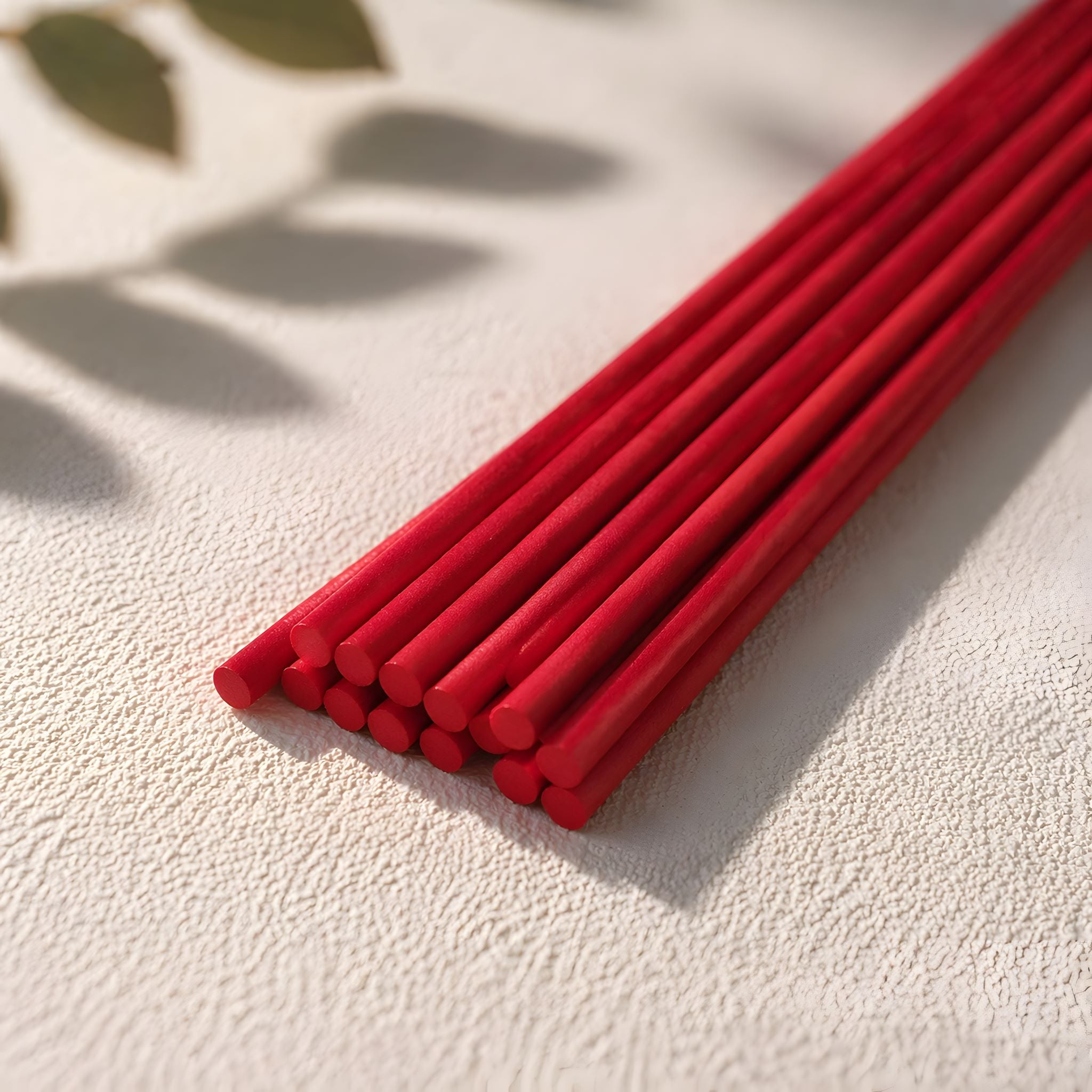 12 inch red diffuser reeds on a textured white surface with a natural light background