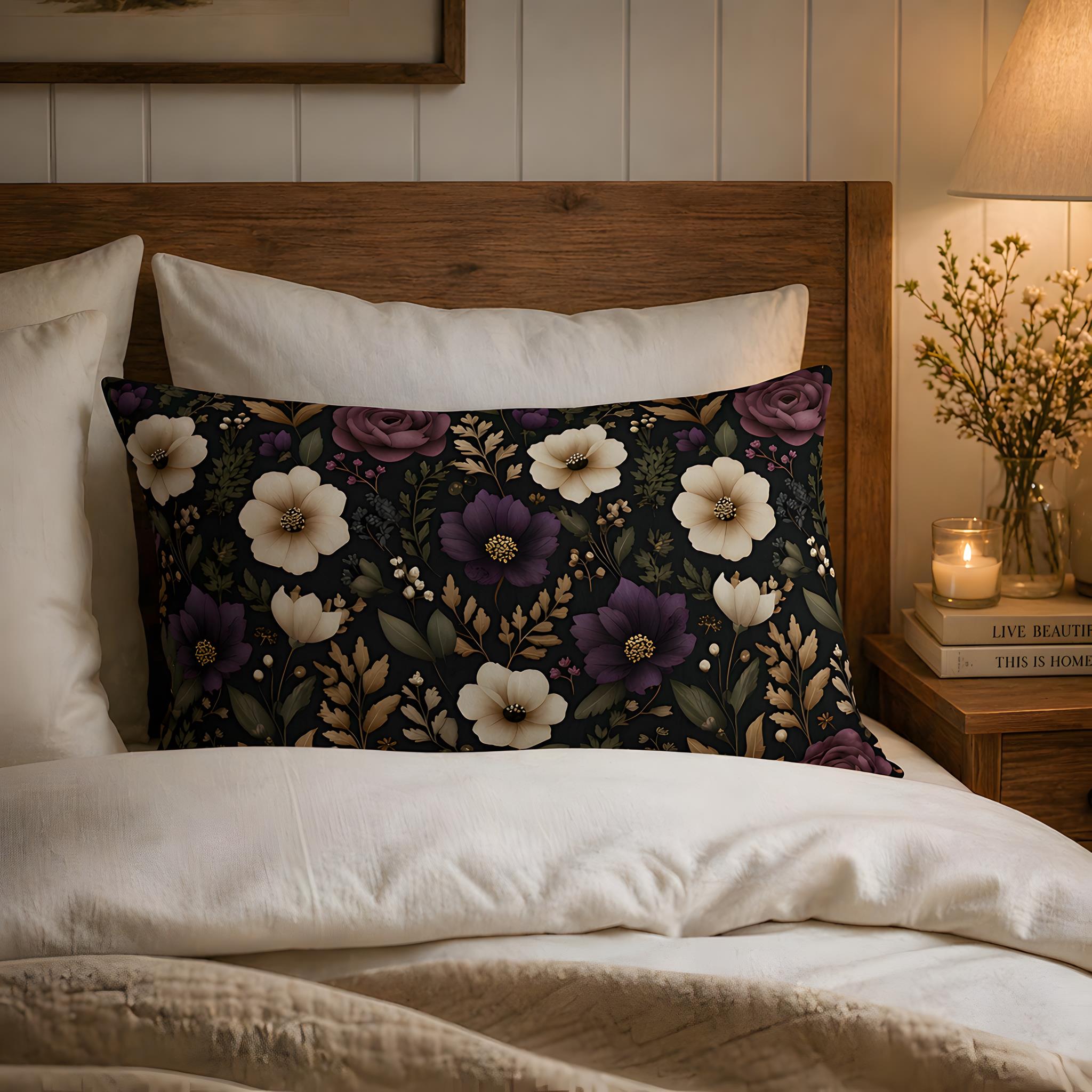 Plum and ivory flower pillow on a bed with a wooden headboard and candlelit nightstand.
