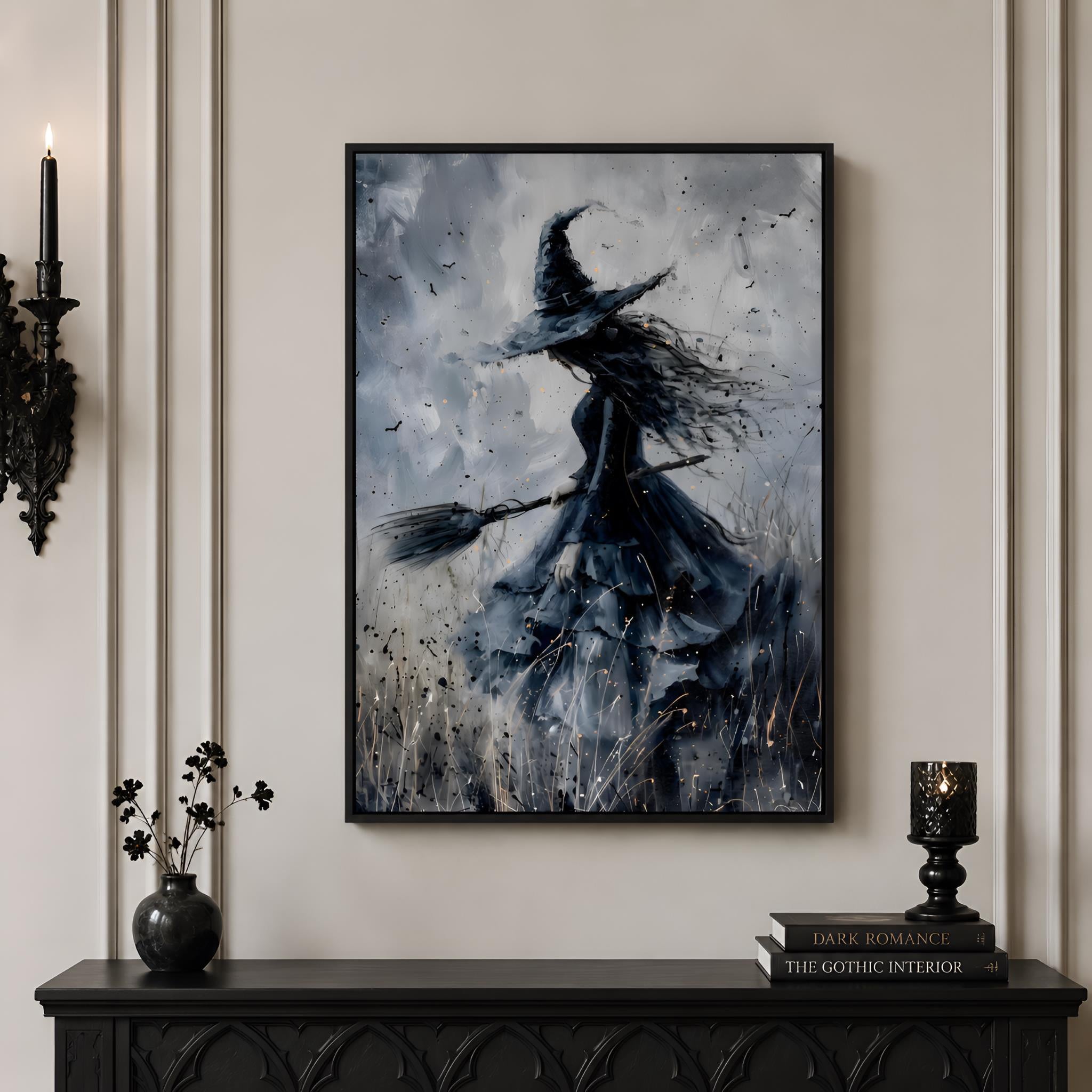 Hanging artwork of a witch on a broomstick in a black frame, hanging on a whimsigoth wall above a dark console table.
