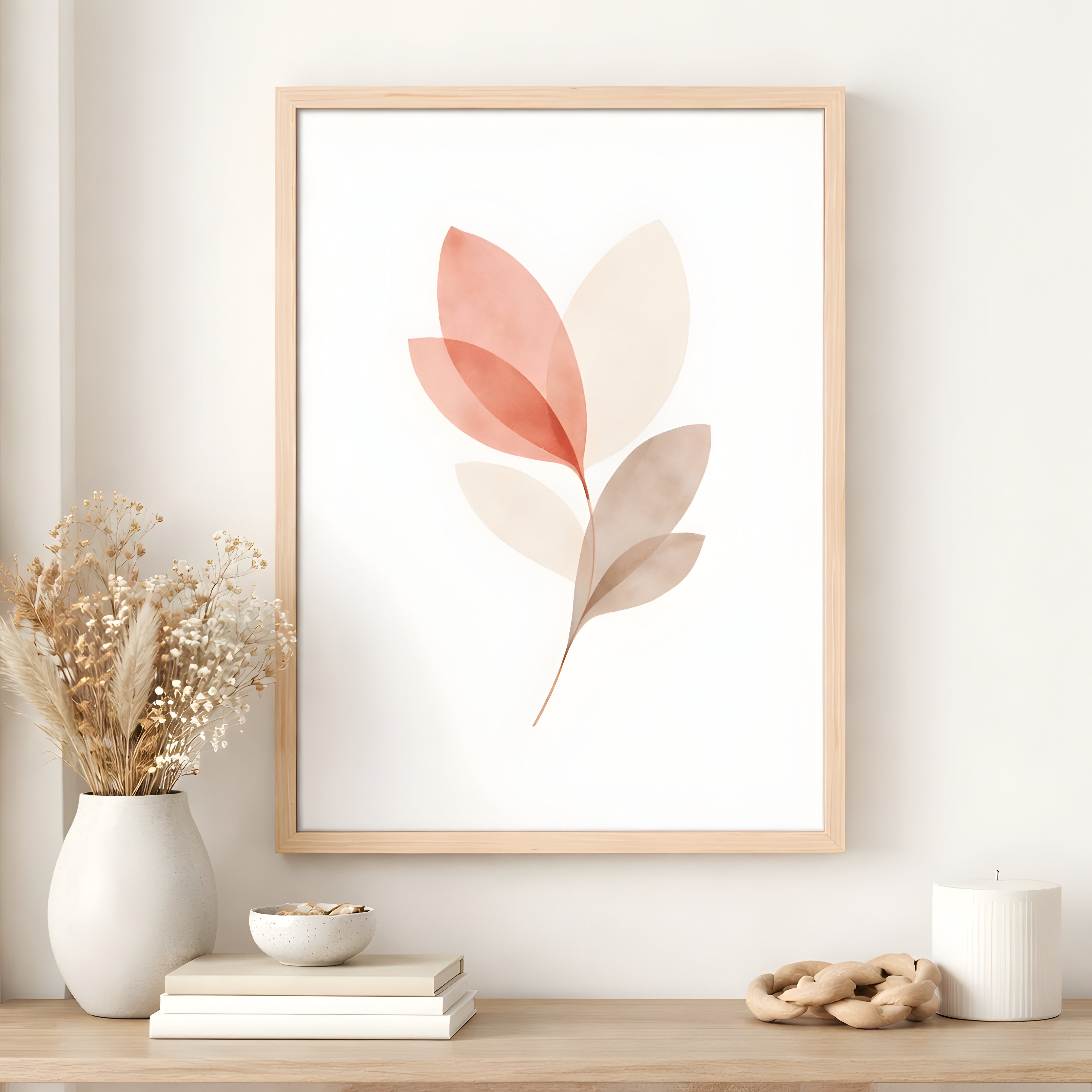 Framed abstract art of leaves on a wall in a natural wood frame above a wooden shelf with decor items.